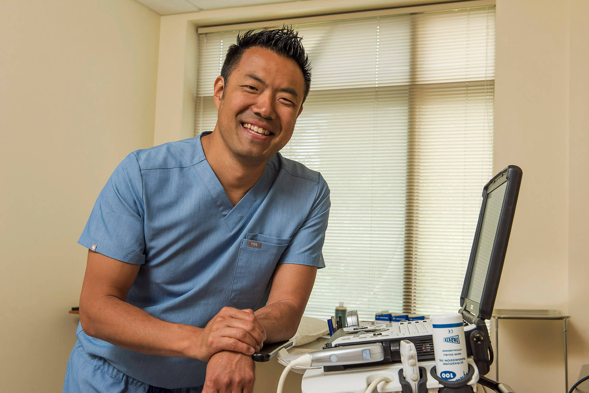 Doctor wearing blue scrubs in exam room